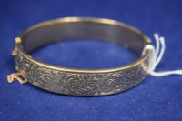 Lot 22 - A 9ct. yellow gold bangle, half engraved with...