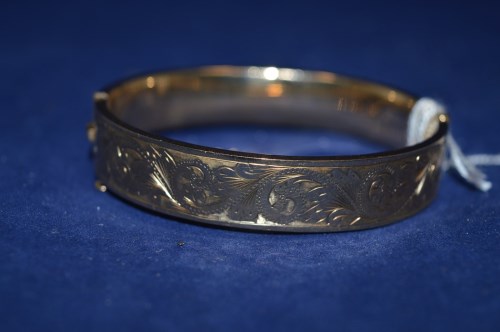 Lot 199 - A 9ct. yellow gold bangle, half engraved with...