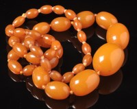 Lot 703 - An amber necklace, the oval beads graduating...