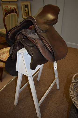 Lot 194 - Three leather saddles and stand