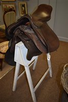 Lot 194 - Three leather saddles and stand