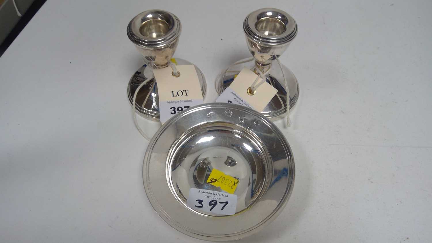 Lot 397 - A pair of silver dwarf candlesticks; and a small alms dish