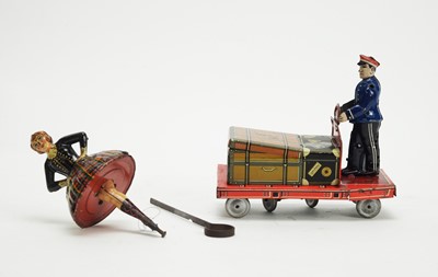 Lot 1138 - A tinplate flywheel Scottish dancer; and a Post War German clockwork luggage trolley.
