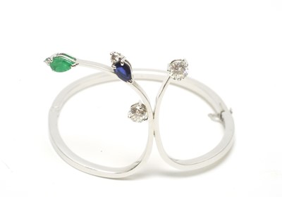 Lot 63 - A diamond, sapphire and emerald set bangle.