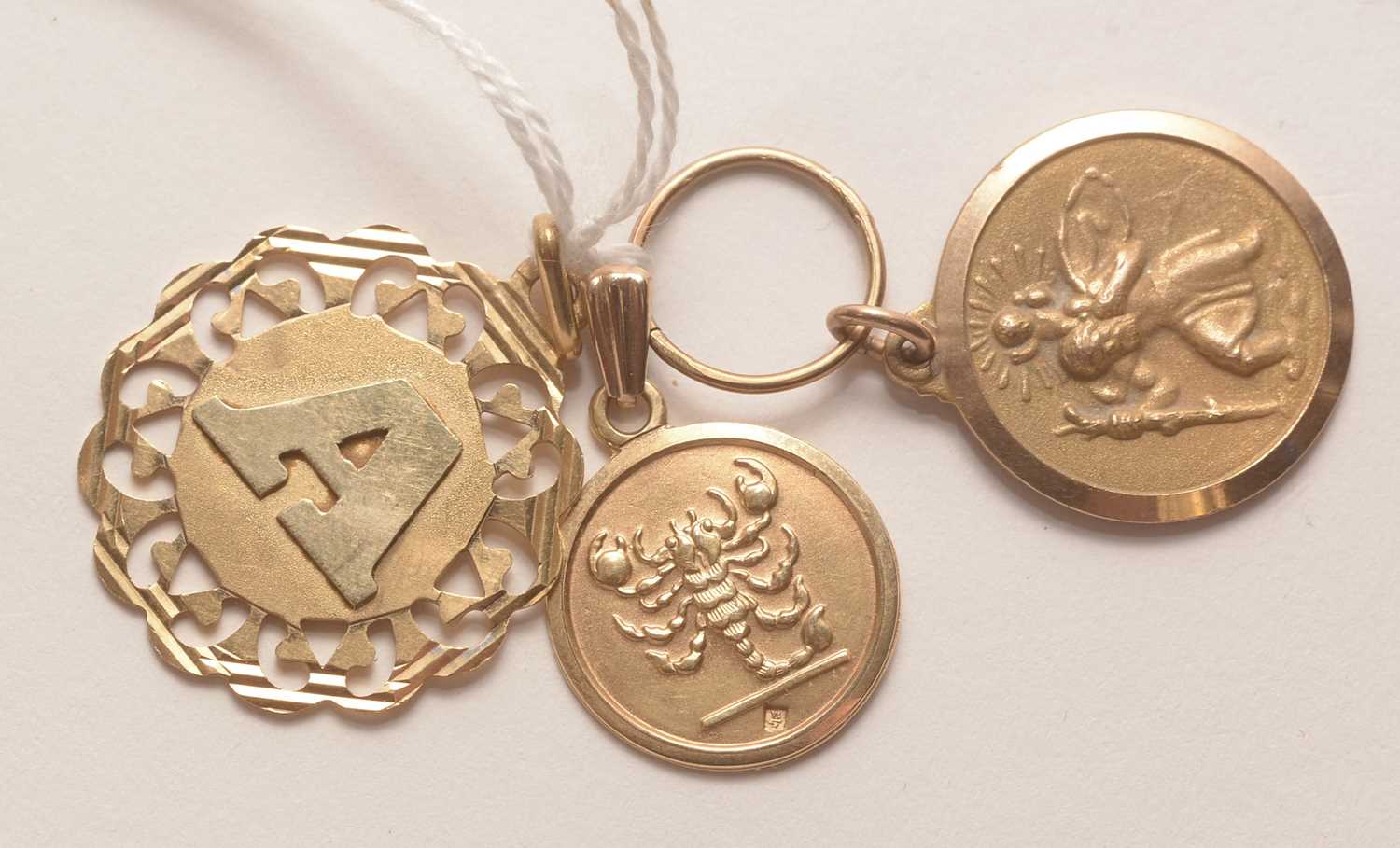 Lot 204 - Three yellow metal pendants.