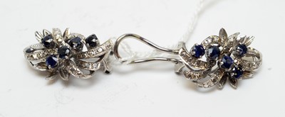 Lot 127 - A pair of high carat white metal, diamond, and sapphire statement ear clips.