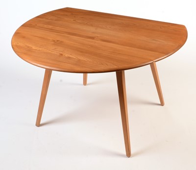 Lot 56 - Ercol: a light beech and elm round-shaped drop-leaf dining table.