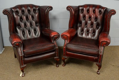 Lot 37 - A pair of red leather wing-back armchairs.