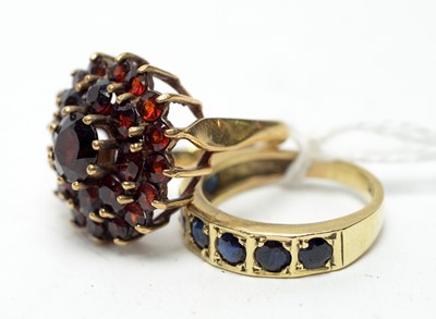 Lot 155 - A 9ct gold and sapphire eternity ring and a 9ct gold garnet dress ring