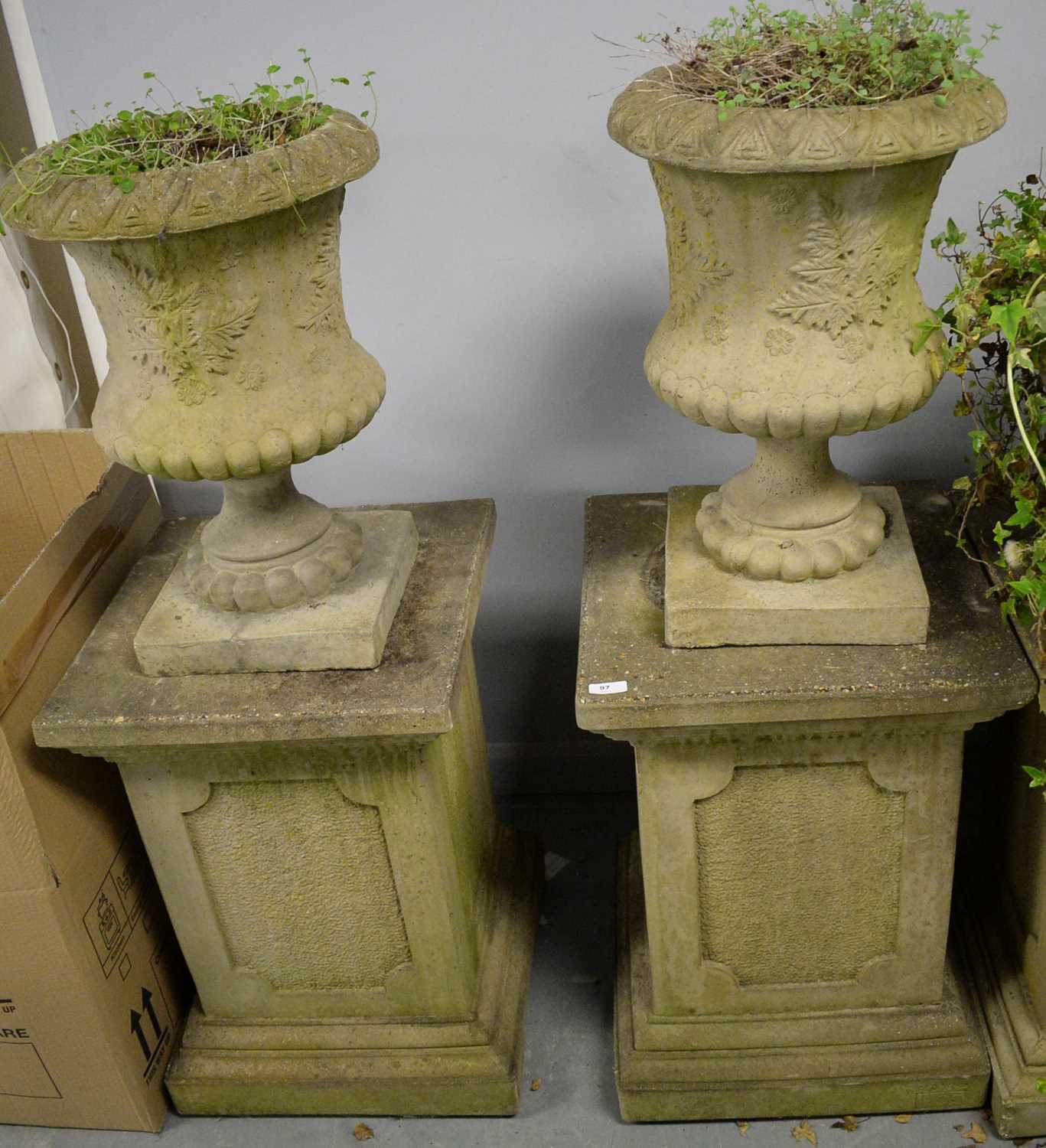Lot 97 - A pair of reconstituted stone urns on pedestals.