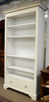 Lot 54 - A cream painted open bookcase.