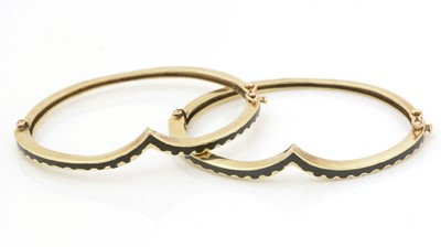 Lot 498 - A pair of 14ct yellow gold and black enamel bangles