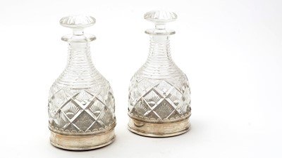 Lot 19 - A pair of George V silver wine coasters; together with a pair of cut glass decanters and stoppers
