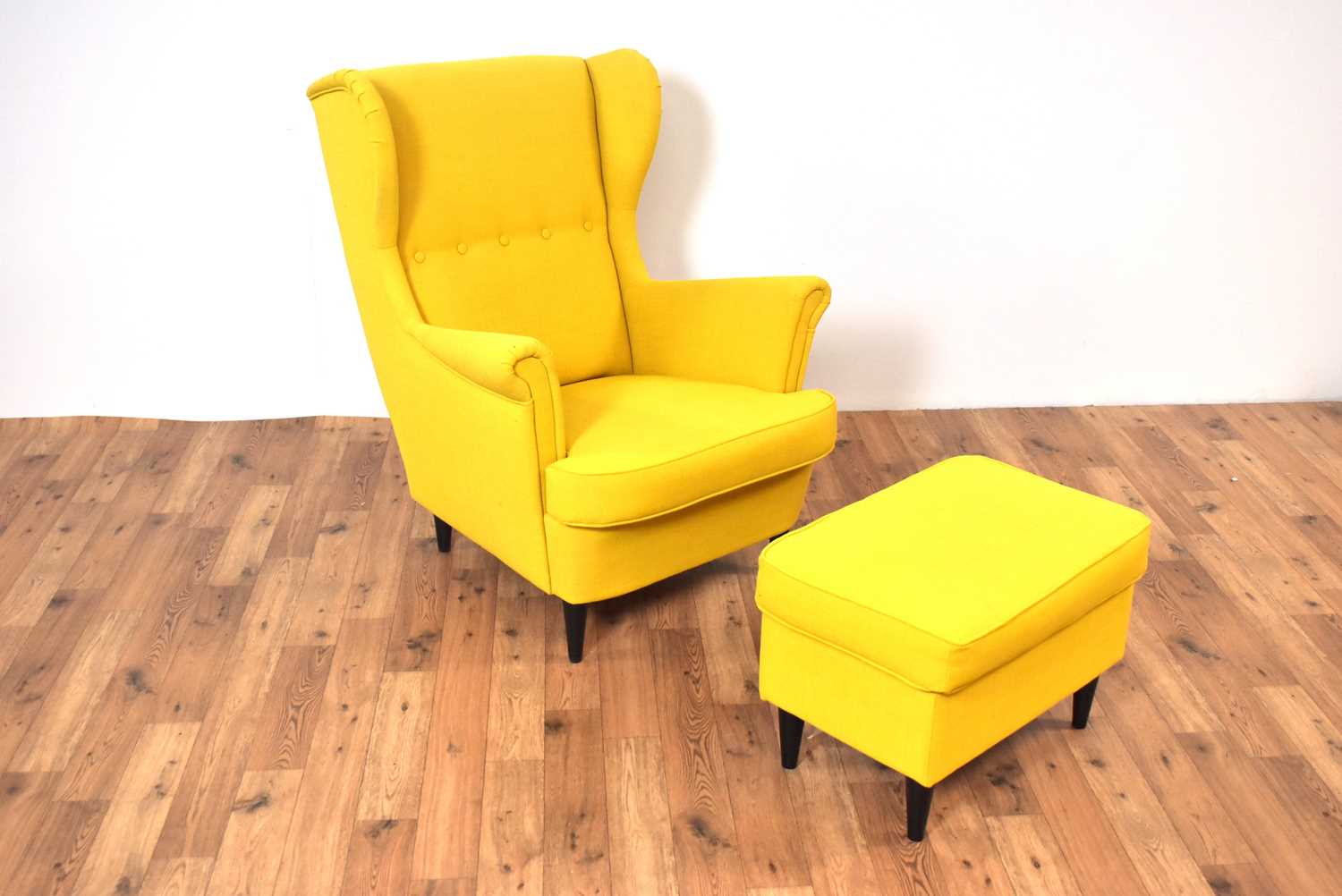 Lot 26 - A contemporary wingback armchair upholstered in vibrant yellow fabric with ottoman