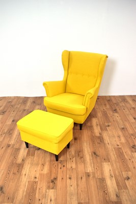 Lot 26 - A contemporary wingback armchair upholstered in vibrant yellow fabric with ottoman