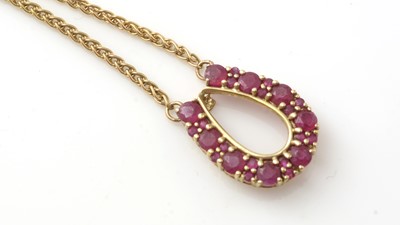 Lot 190 - A horseshoe pattern ruby pendant in 9ct yellow mount on twist link chain