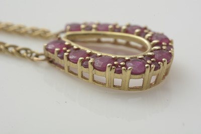 Lot 190 - A horseshoe pattern ruby pendant in 9ct yellow mount on twist link chain