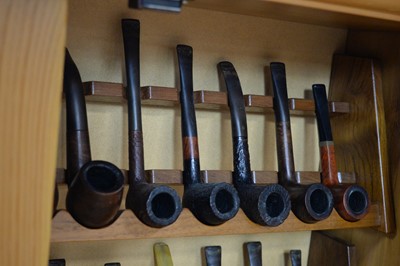 Lot 424 - A collection of tobacco pipes contained in a pine wall mounting cabinet