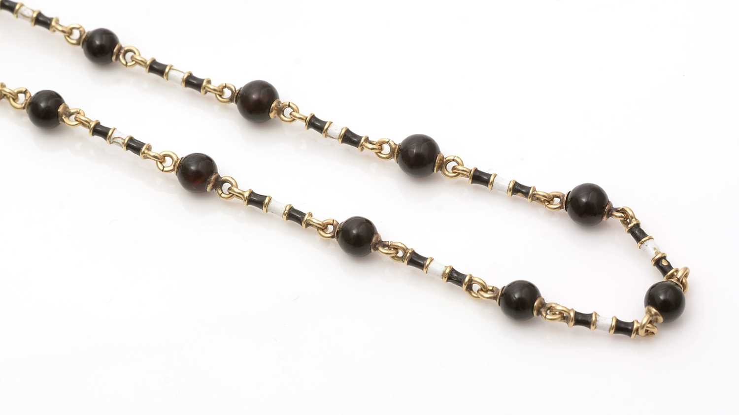 Lot 662 - An onyx, enamel and gold muff chain necklace