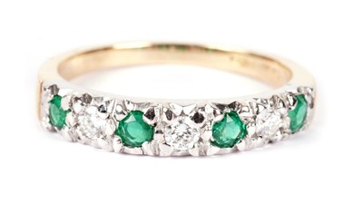 Lot 1304 - An emerald and diamond half-hoop eternity ring