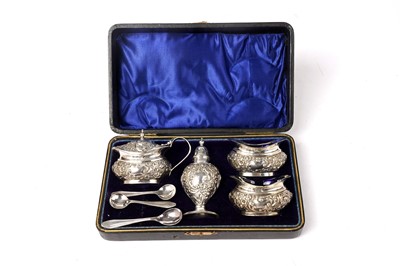 Lot 1668 - An Edwardian silver four-piece condiment set; and three non-matching plated spoons