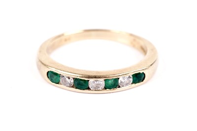 Lot 547 - An emerald and diamond half hoop eternity ring