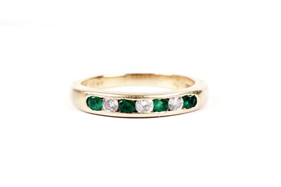 Lot 547 - An emerald and diamond half hoop eternity ring