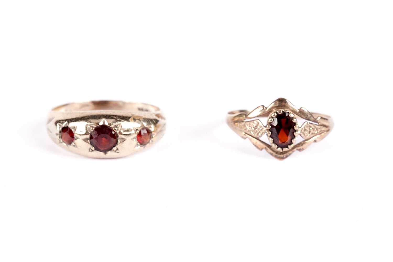 Lot 521 - A garnet three stone band; and another garnet ring