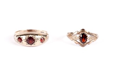 Lot 521 - A garnet three stone band; and another garnet ring