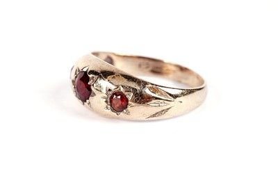 Lot 521 - A garnet three stone band; and another garnet ring