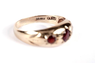 Lot 521 - A garnet three stone band; and another garnet ring