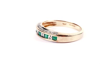 Lot 638 - A diamond and emerald half hoop eternity ring