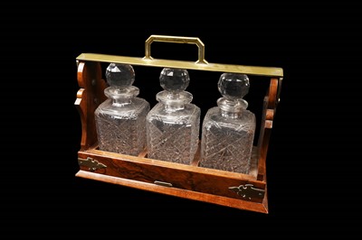 Lot 273 - A 20th Century walnut three bottle tantalus fitted with three cut-glass decanters and stoppers