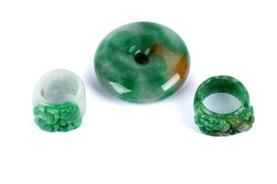 Lot 181 - A Chinese jadeite disc pendant; and two carved jadeite thumb rings