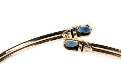 Lot 173 - A sapphire set crossover bangle