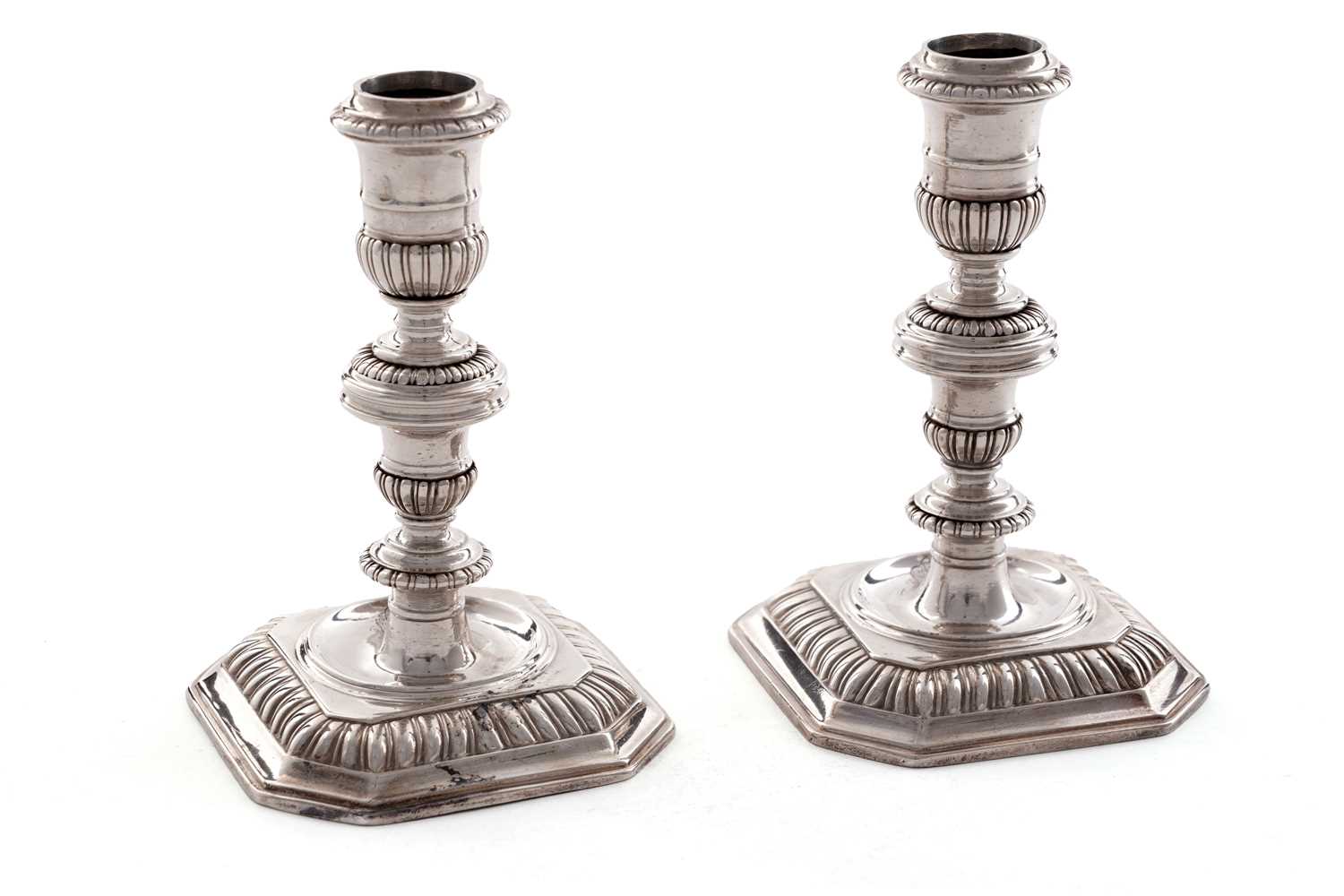 Lot 66 - A pair of William III silver cast candlesticks