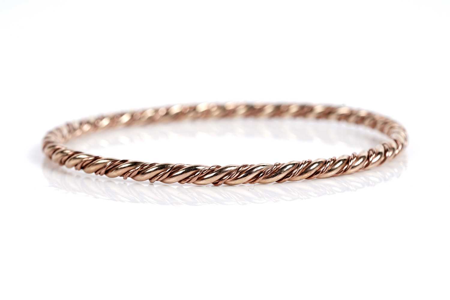 Lot 630 - A 9ct rose and yellow gold twist pattern bangle
