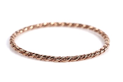 Lot 630 - A 9ct rose and yellow gold twist pattern bangle