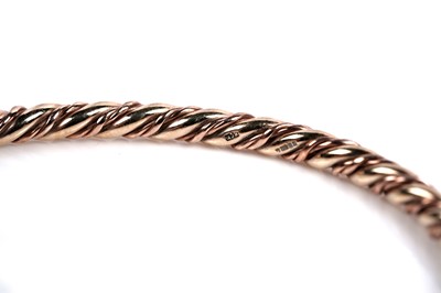 Lot 630 - A 9ct rose and yellow gold twist pattern bangle