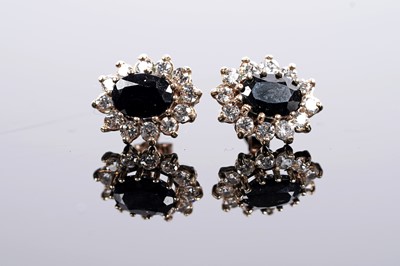 Lot 645 - A pair of sapphire and white stone cluster earrings