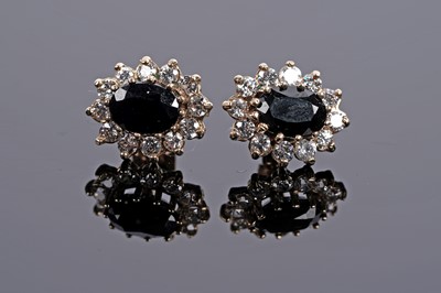 Lot 645 - A pair of sapphire and white stone cluster earrings