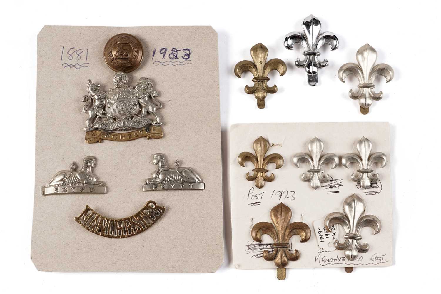 Lot 93 - A display of Manchester Regiment badges, buttons and titles; and fleur-de-lys badges
