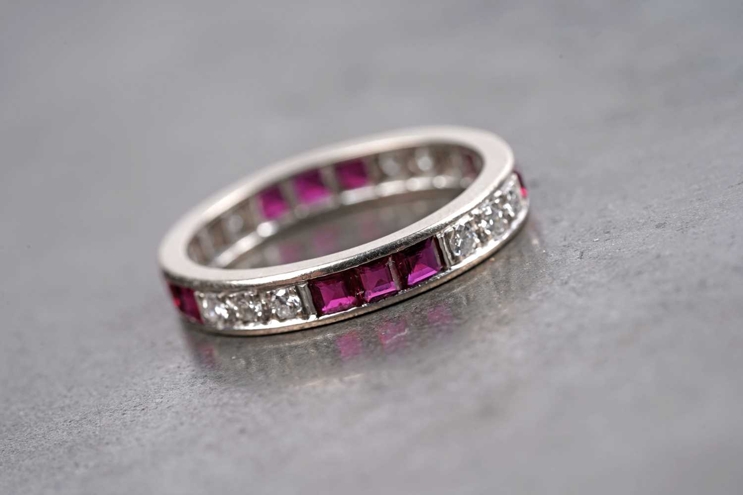 Lot 585 - A ruby and diamond eternity ring