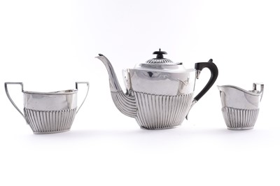 Lot 365 - An Edwardian half-fluted silver teapot; and an Edwardian silver sugar bowl and milk jug