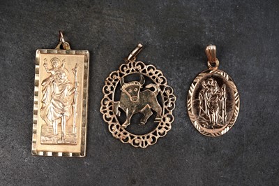 Lot 154 - Two gold St Christopher pendants; and a Taurus zodiac pendant