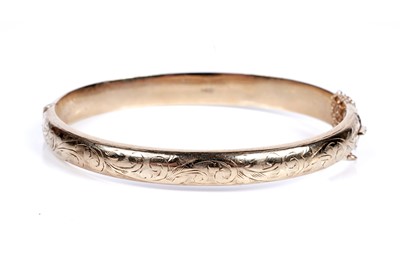 Lot 95 - A 9ct gold hinged bangle with engraved foliate decoration