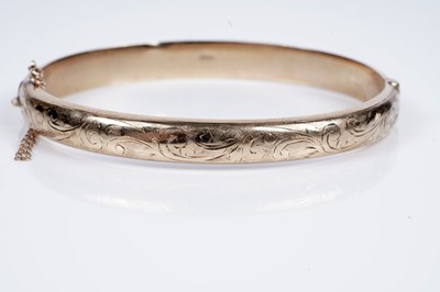 Lot 95 - A 9ct gold hinged bangle with engraved foliate decoration