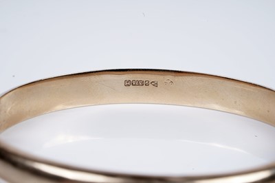 Lot 95 - A 9ct gold hinged bangle with engraved foliate decoration