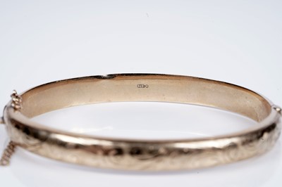 Lot 95 - A 9ct gold hinged bangle with engraved foliate decoration