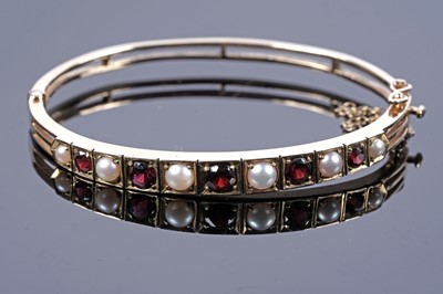 Lot 13 - An Edwardian stye garnet and pearl bangle